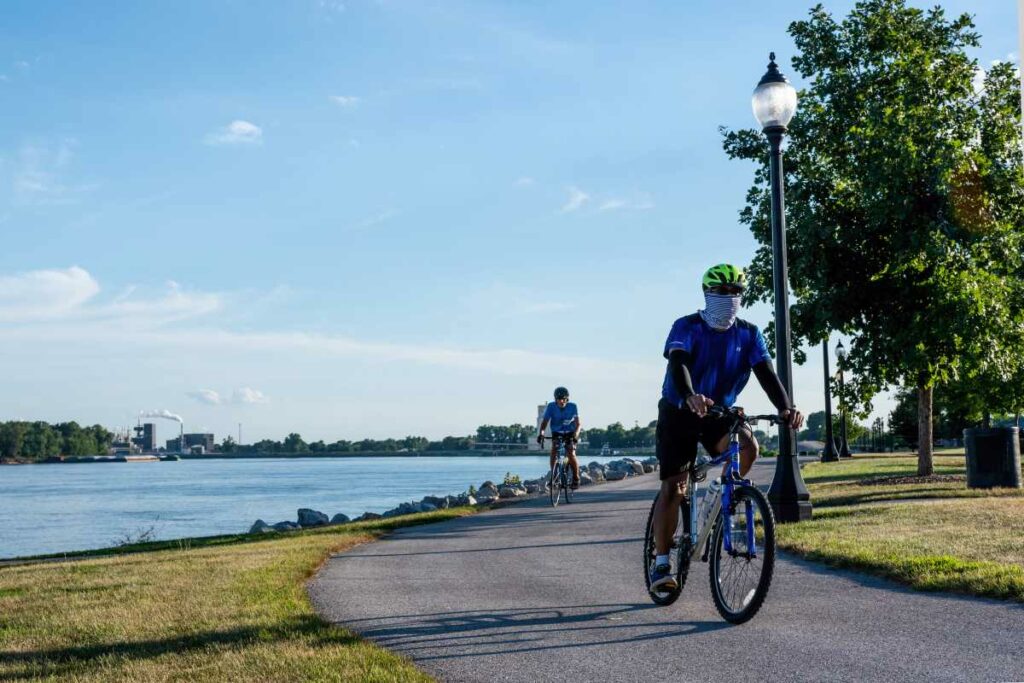  Two men getting exercise by riding bikes on a bike trail along the Mississippi River waterfront 